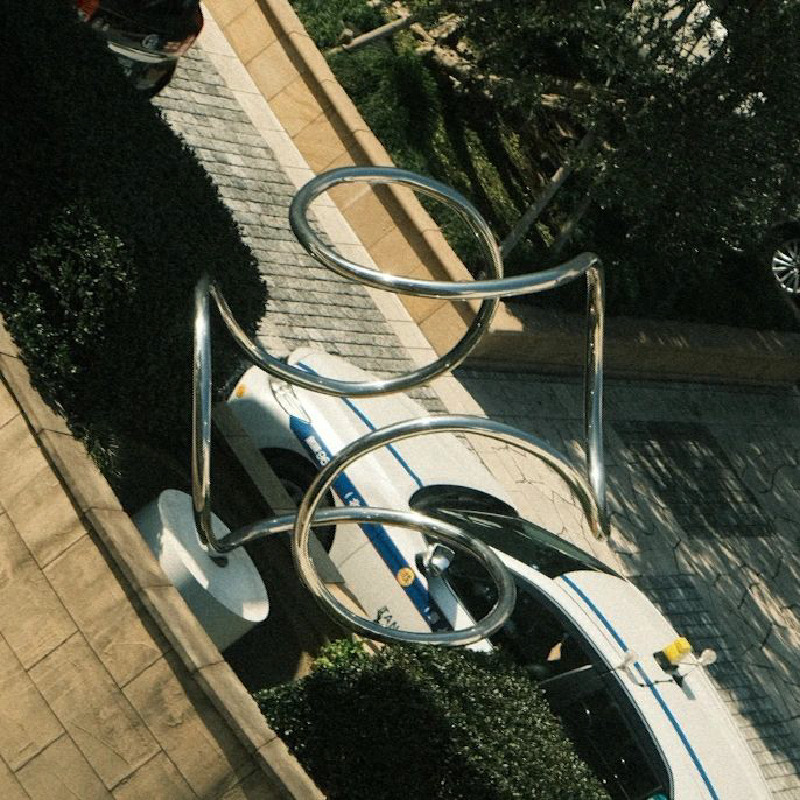 A photograph of a twisted metal sculpture. The overall sculpture is spherical, but the picture is taken at an angle that makes it look like a plus sign.